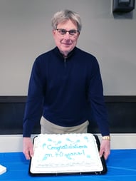 Barry Schweer hold up 40th work anniversary cake with Heartland Bank