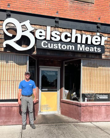Owner of Belschner's Custom Meats, Casey Mitchell, standing in front of their building.