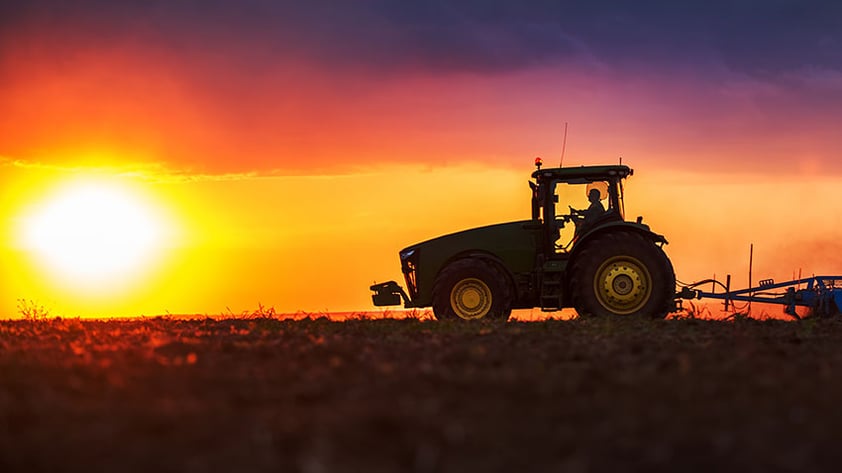 Tractor in field at sunset